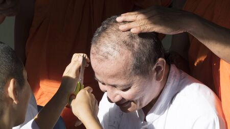 Lampang, Thailand - July 18, 2016: people cut hair of man who will become buddhism monk in ordination ceremony at Bunyanupab temple in Lampang, Thailand on July 18, 2016.のeditorial素材