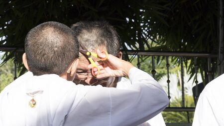 Lampang, Thailand - July 18, 2016: people cut hair of man who will become buddhism monk in ordination ceremony at Bunyanupab temple in Lampang, Thailand on July 18, 2016.のeditorial素材