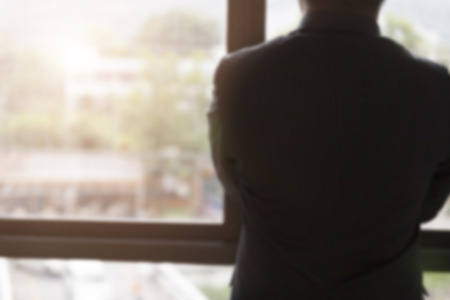 back of businessman in suit looking out through office window - blur for use as backgroundのeditorial素材