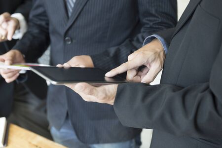 group of businessman meeting, analyzing and discussing with tablet and documentの写真素材