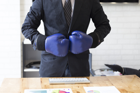 businessman in necktie and suit with blue boxing gloves - business competition conceptの写真素材