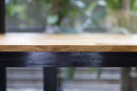 wooden table beside window with green leaves background for montage or display your productの写真素材