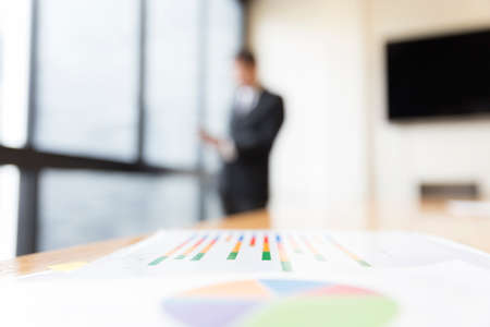 business analysis chart report with background of businessman in suit standing beside office windowの写真素材