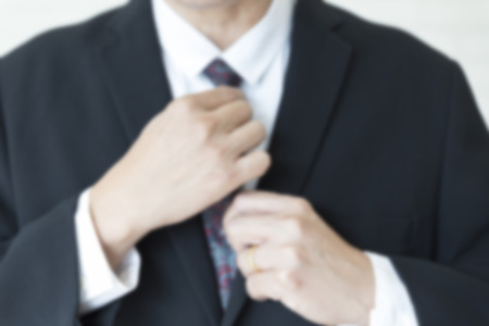 businessman in black suit arrange his necktie - blur for use as backgroundの写真素材