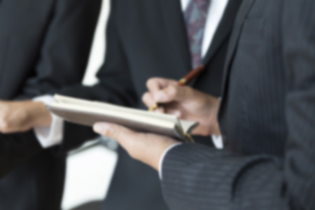 group of businessman meeting, analyzing and discussing with pen and notebook- blur for use as backgroundの写真素材