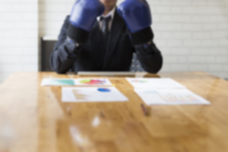 businessman in necktie and suit with blue boxing gloves - business competition concept - blur for use as backgroundの写真素材