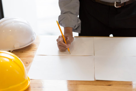 architect holding pencil working on blueprint of construction project in workplace