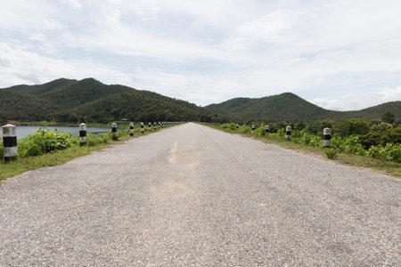 scenery of road beside mountain hill and pond