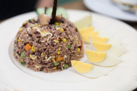 fried brown rice with pea, carrot, corn, egg and salted fish on white dish, Thai cuisineの写真素材
