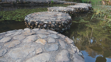 rock pavement as walk bridge across the calm pondの写真素材