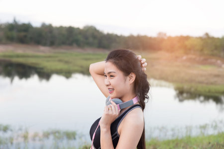 fitness, sport and healthy lifestyle concept - happy teenage woman or sportswoman with earphones outdoors in parkの写真素材