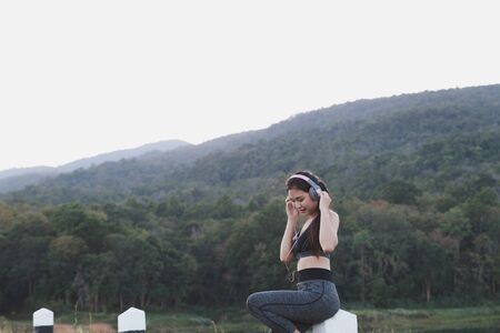 fitness, sport and healthy lifestyle concept - happy teenage woman or sportswoman with earphones outdoors in parkの写真素材