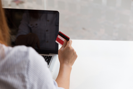 Woman's hands holding a credit card and using laptop computer for online shopping paymentの写真素材
