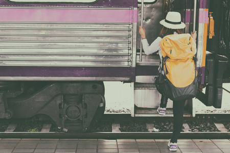 Traveler holding and stepping up to a train with backpack for journey travel at train station. Travel concept.の写真素材