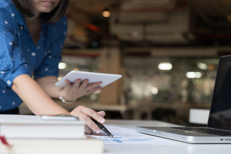Working woman hand holding pen with digital tablet and Business summary or Business plan report with Charts and graphs in Business conceptの写真素材