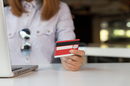 Woman's hands holding a credit card and using laptop computer for online shopping paymentの写真素材