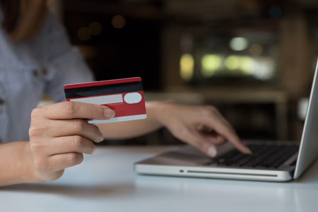 Woman's hands holding a credit card and using laptop computer for online shopping payment