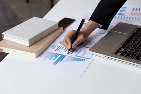 Working woman hand holding pen with Business summary or Business plan report with Charts and graphs in Business conceptの写真素材