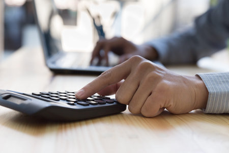 Businessman Analyzing financial data on computer and counting on calculator in office