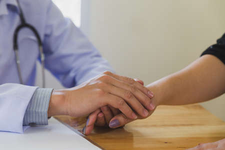 medical doctor holing female patient's hands and comforting herの写真素材
