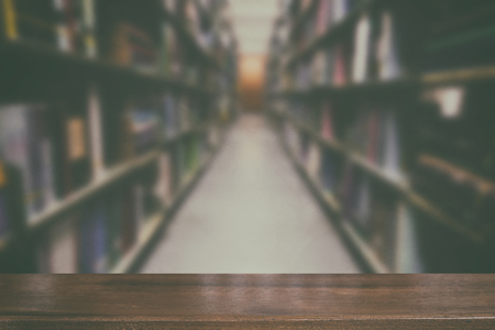 interior of modern library with gray book shelves, blur background with selective focus wood table for display your productの写真素材