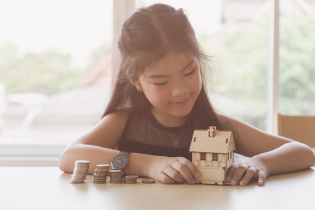 asian girl hold little house with money pile stack - money saving education conceptの写真素材