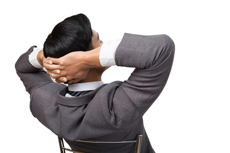 back view of business man wearing gray suit sitting and relaxing on chair with white background. Rear or backside view of business personの写真素材