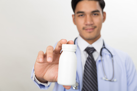 smiling young Doctor, physician with drug in the hands at workplace. Panacea, life save service, prescribe medicine, legal drug store, disease healingの写真素材