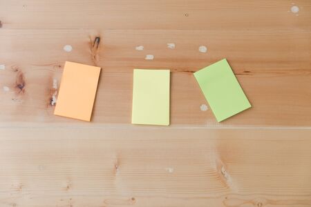 Flat lay of office and business stationery supplies - colorful sticky notes on wooden desk board background, top view with copy spaceの写真素材