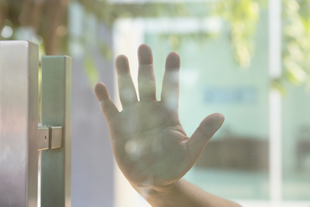 Man's hand pushing, opening glass door from outsideの写真素材