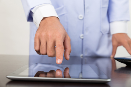 Male doctor hand working with modern digital tablet or touchpad and laptop computer at workplace - Medical technology concept.の写真素材