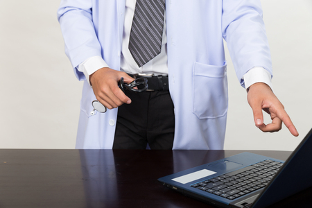 Male doctor holding stethoscope and pointing at computer screen showing something in medical office clinic - Medical technology concept.の写真素材