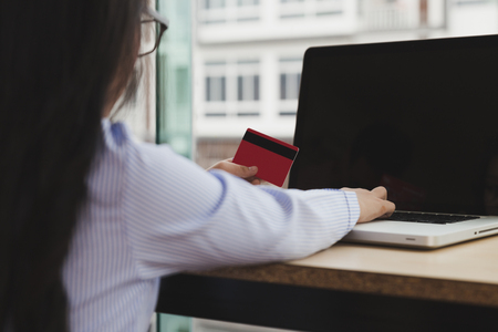 young asian girl holding credit card and using laptop computer for purchasing from internet. online shopping conceptの写真素材