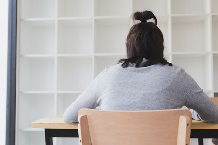 asian girl female teenager student sitting beside white bookshelf at schoolの写真素材
