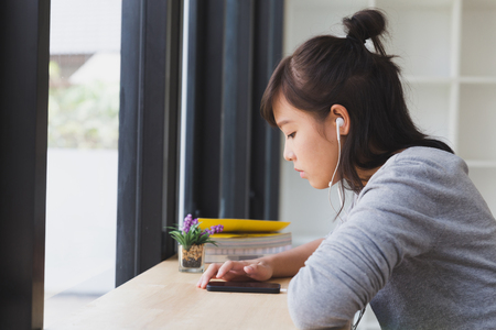 asian girl female teenager student wearing headphones and listening to music in smart phoneの写真素材