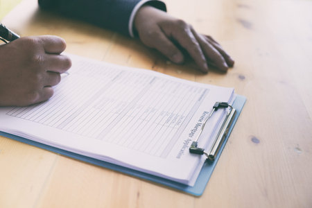 man 's hand fill out reverse mortgage loan application on a clipboard. A form to be filled by a...
