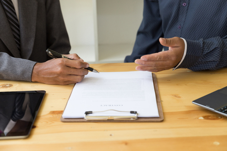 successful businessman with a contract giving a hand - presenting & signing business document with partnerの写真素材