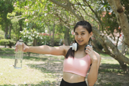 young beautiful asian fitness athlete woman holding drinking water after work out exercising at...