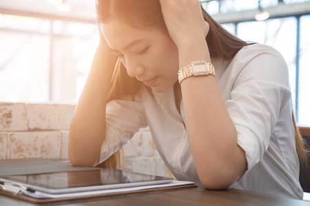 young asian woman put hand on head feeling tired, frustrated and stressed from hard work while...