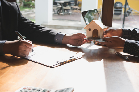 realtor talk with his clients.  real estate agent have a deal with a couple. House developer and customer have a meeting. businessan with a man and woman. sale and purchase property with house model and signing contract documentの写真素材