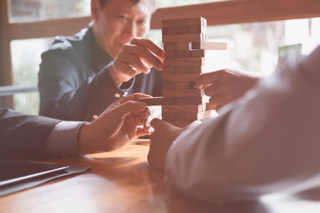 group of businessman pulling out wood building block from tower. Business strategy and planning.