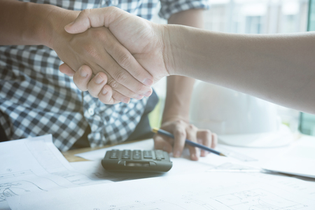 young architect and customer shaking hands at workplace. Engineer handshaking with partner for successful deal in building project development. business teamwork, cooperation, success collaboration conceptの写真素材