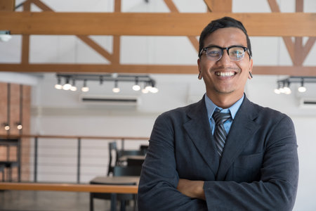 successful asian businessman at workplace. confident young man wearing blue suit standing at office.