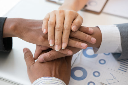 young asian businessman joining united hand, business team touching hands together after complete a...