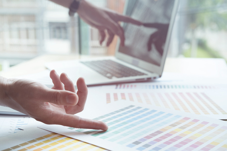 young male graphic designer working with computer, color swatch sample colour catalog. creative man using digital tablet at modern office.  Architectural drawing with work tools and accessories. business, technology, design and people conceptの写真素材