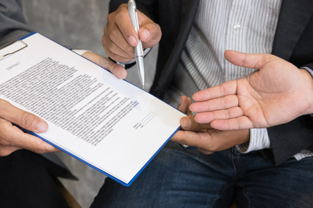 Businessman and lawyer negotiating a contract, they are pointing on a document and discussing together in a meeting. business colleagues working at office workplaceの写真素材