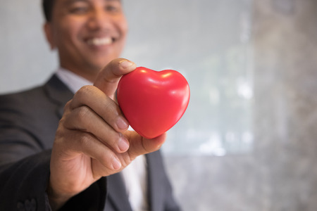 young businessman in a business suit shows big red heart at office workplace. love my job conceptの写真素材