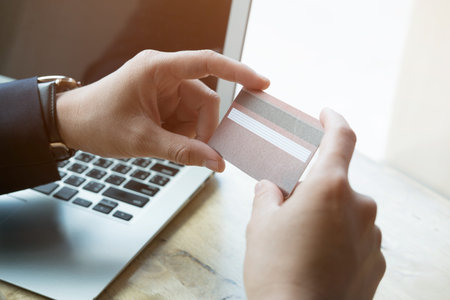 young male holding a credit card and using laptop computer for online shopping. businessman purchase...