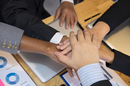 young asian businessman joining united hand, team of business people touching hands together after complete a deal in meeting - unity, harmony, teamwork, partnership, collaboration, corporate concept.の写真素材