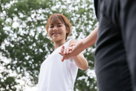 happy young asian couple holding hands in garden. Boyfriend and girlfriend walking in public park. Love, romance and relationship conceptの写真素材